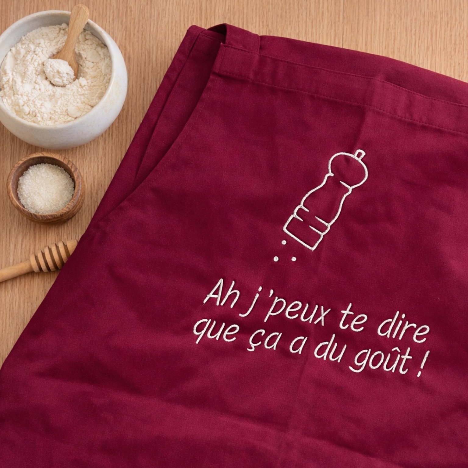 Tablier de Cuisine Brodé sur un plan de travail avec farine et miel