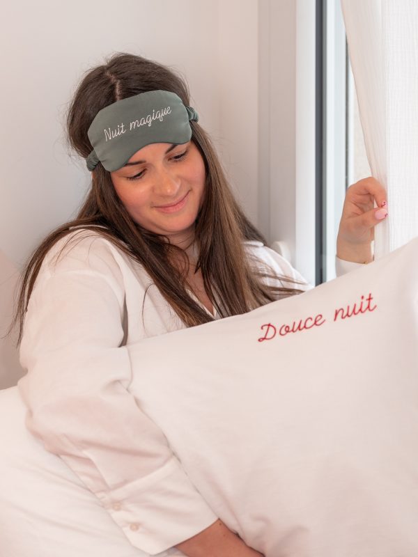 Femme qui porte le masque personnalisable couleur vert sauge avec dans la main un oreiller personnalisé en coton