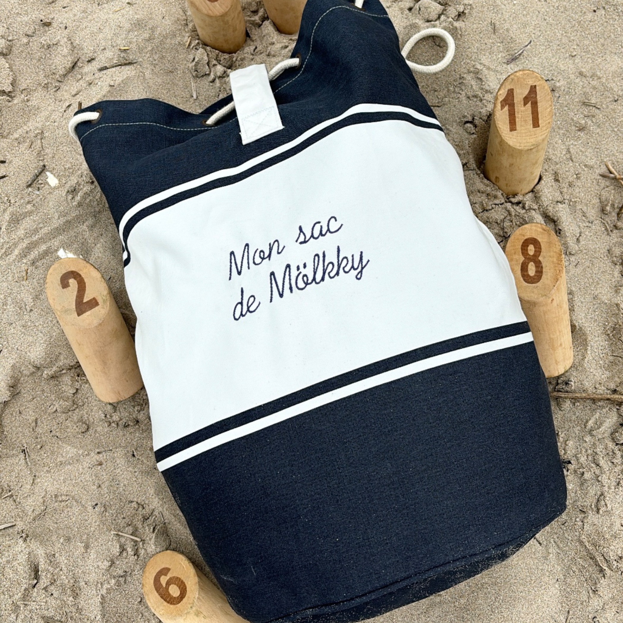 Sac à Molkky Personnalisé dans le sable avec des quilles autour